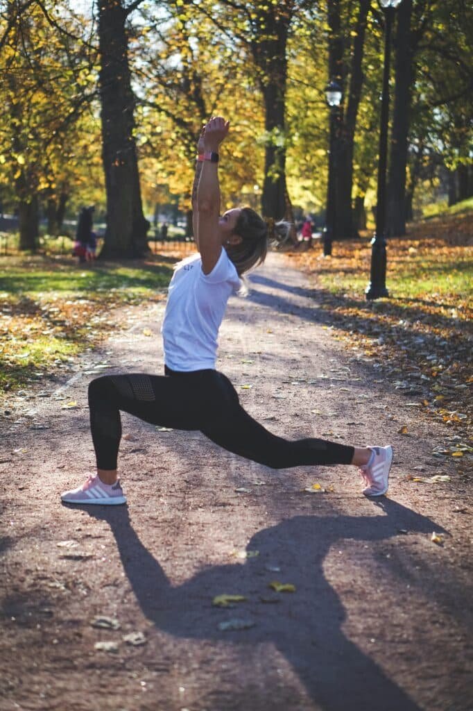 A young woman performing lunges and stretching before a run to improve her running speed. 